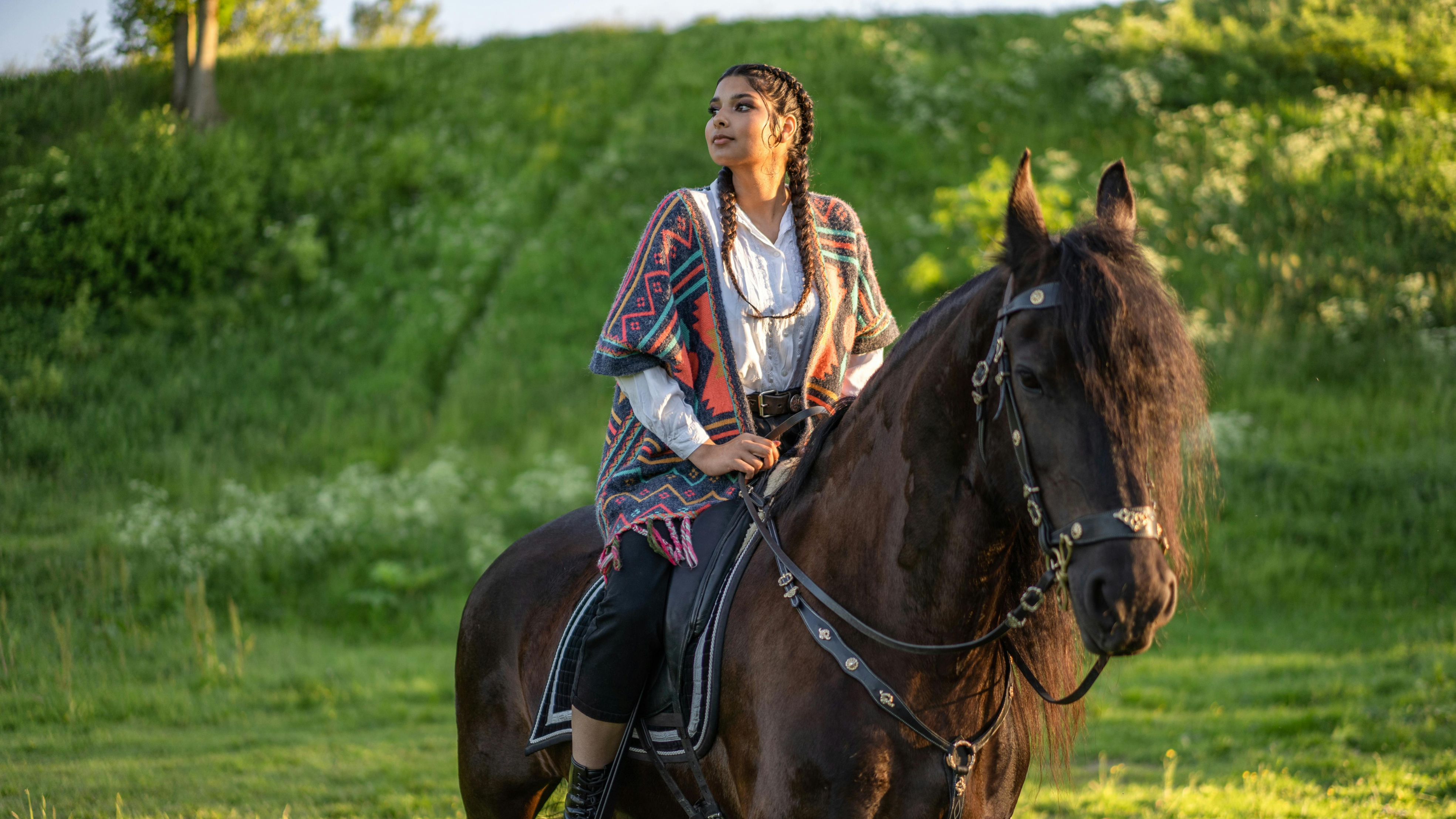 Image of girl on a horse with green grass in the background.