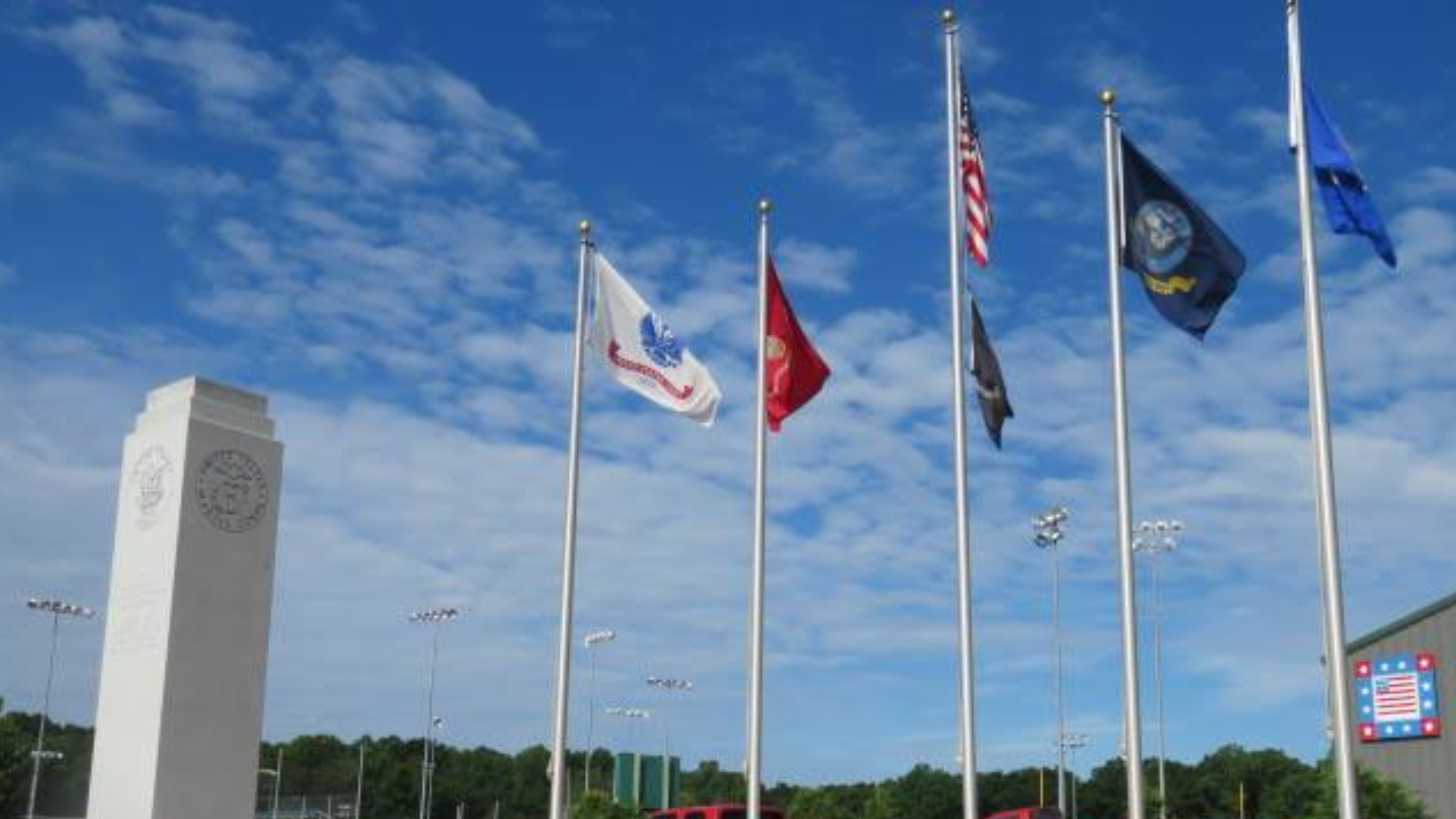 Image of a memorial stone to honor veterans with flags waving nearby.